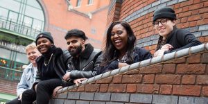 Picture of 5 representatives from beatfreeks leaning on a wall smiling